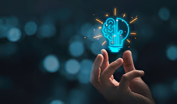 Hand holding a glowing light bulb with a brain design, symbolizing innovation and creative thinking.